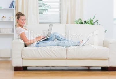 Blonde woman working on laptop on the couch