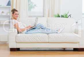 Blonde woman working on laptop on the couch