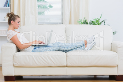 Blond woman looking at the laptop on the couch