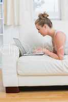 Woman using the notebook while lying on the sofa