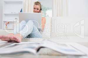 Woman calling and using laptop in living room