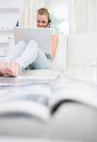 Woman sitting on the couch while using laptop and calling