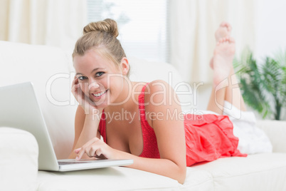 Smiling woman using notebook while holding her cheek