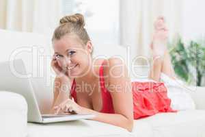 Smiling woman using notebook while holding her cheek