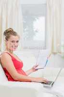 Woman holding cheerfully a notepad and laptop
