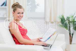 Woman looking at camera and holding laptop and notepad