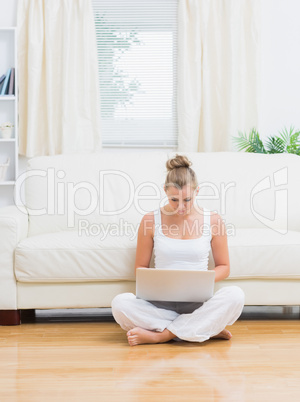 Woman typing on laptop while sitting on the floor