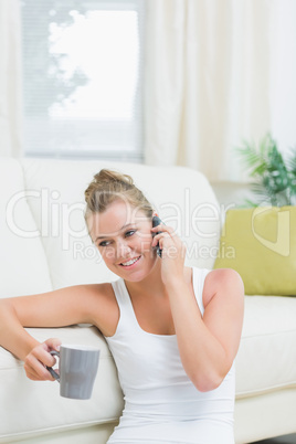 Woman using mobile phone while drinking coffee