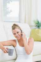 Woman using mobile phone while drinking coffee
