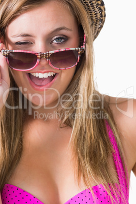 Blonde winking while holding sun glasses