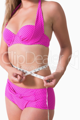 Woman wearing bikini while measuring waist