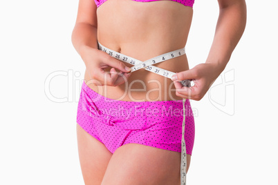 Woman wearing bikini while measuring waist