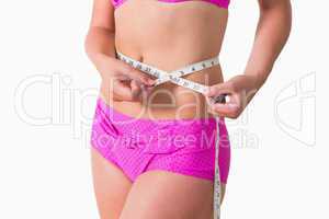 Woman wearing bikini while measuring waist
