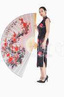 Woman in kimono standing with large silk fan