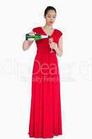 Woman in red dress pouring glass of champagne