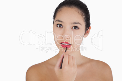 Woman putting on lipstick with a brush