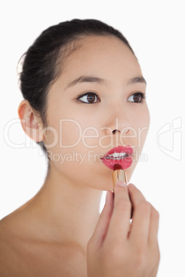 Woman putting on pink lipstick