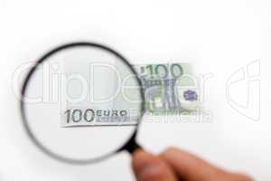 Hand holding magnifying glass over euro note