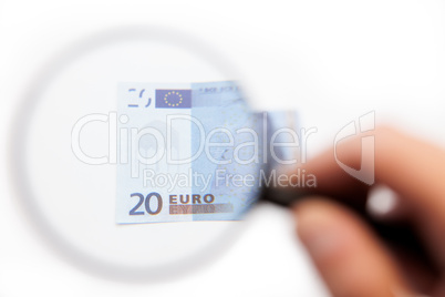 Hand using magnifying glass on euro note