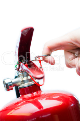 Hand pulling safety pin from fire extinguisher