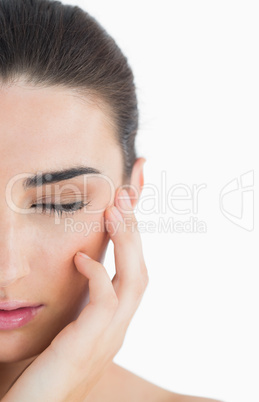 Woman having eyes closed while touching her cheek