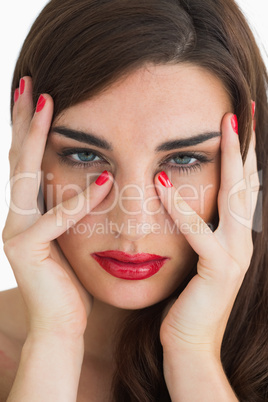 Woman touching her face while wearing red lipstick