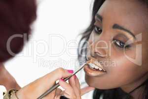 makeup artist applying golden lip gloss