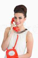 Woman dressed in sixties style holding an old phone