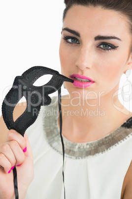 Woman dressed in sixties style holding a mask