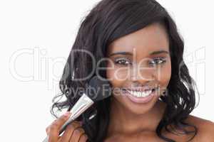 Smiling woman using makeup brush