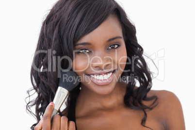Woman smiling while holding a makeup brush