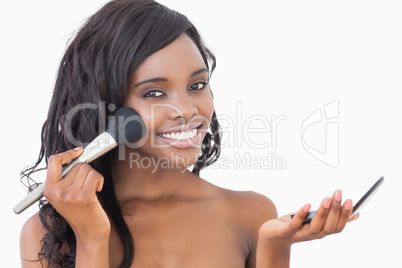 Woman holding powder and a brush to her face