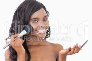 Woman holding powder and a brush to her face
