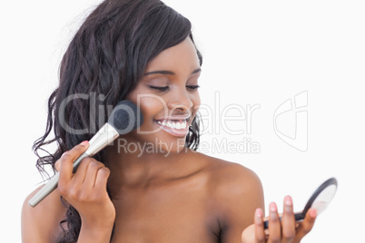 Smiling woman using powder and brush