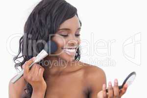 Smiling woman using powder and brush