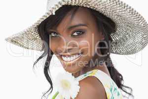 Woman smiling and holding white flower in a sun hat