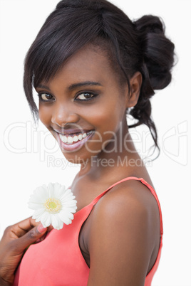 Girl in pink dress holding a flower while smiling