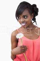 Girl standing holding a flower while smiling against white backg