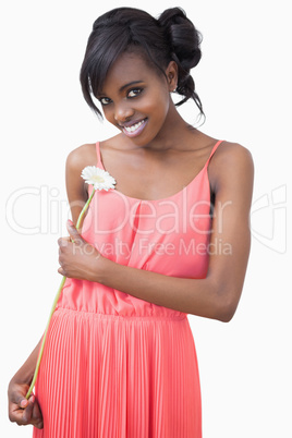 Woman standing holding a flower smiling