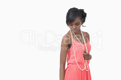 Woman looking down wearing pearls and pink dress