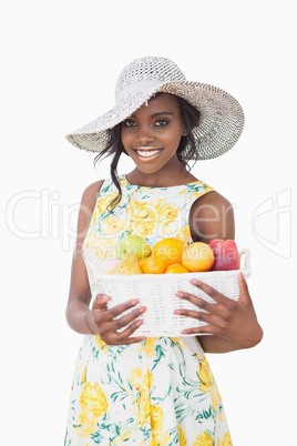 Woman with sun hat holding box with fruits