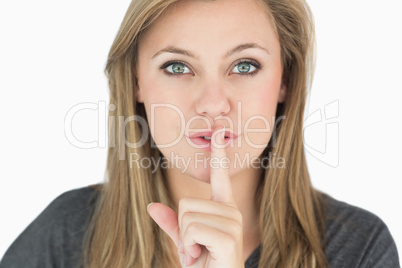 Blond woman putting finger on mouth