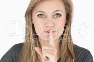 Blond woman putting finger on mouth
