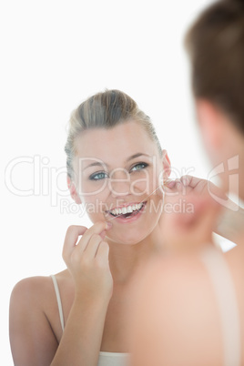 Woman using dental floss in front of mirror