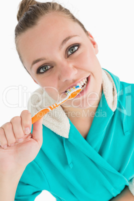 Woman with bathrobe washing her teeth