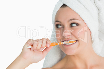 Woman with hair towel washing her teeth