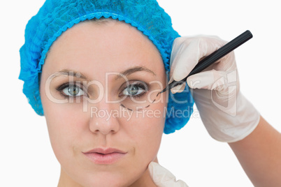 Plastic surgeon writing on woman's face