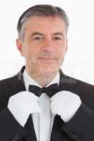 Cheerful waiter adjusting his bow tie