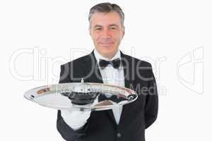 Smiling man holding a hotel bell on a tray