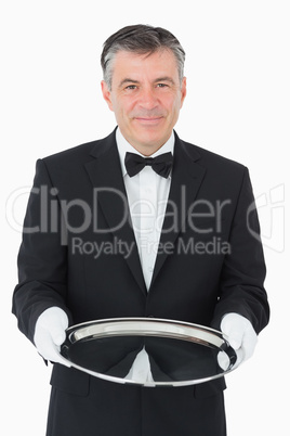 Smiling waiter looking at camera while holding a silver tray